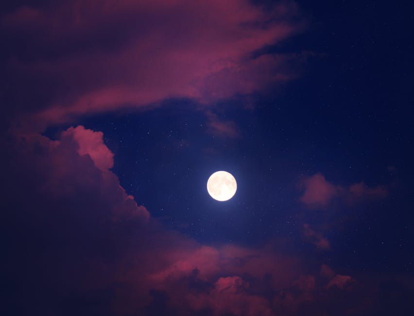 A glowing full moon with clouds and stars